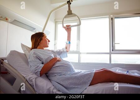 Frau, die aus dem Krankenhausbett hochhebt und den Griff hält Stockfoto