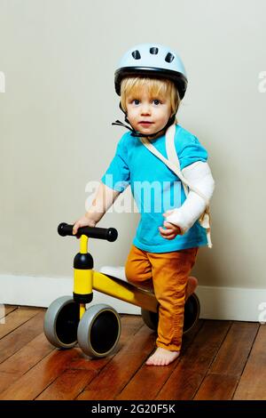 Junge mit gebrochener Hand in Gips und kleinem Fahrrad Stockfoto