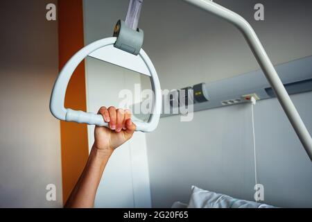 Der Griff des Krankenhauses hängt mit der Hand über dem Bett Stockfoto