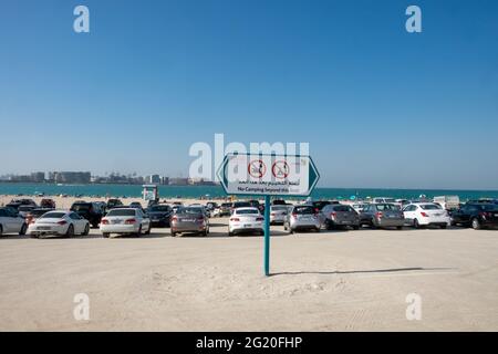 Ein Parkplatz mit Aussicht - Autos an einem der wenigen öffentlichen Strände in Dubai, VAE geparkt. Stockfoto