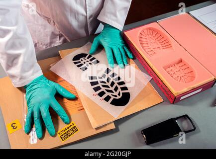 Forensischer Wissenschaftler ungeduldig, weil er in Schuhsohlen-Abzügen im Krimilabor, Konzeptbild, keine Ähnlichkeit finden kann Stockfoto