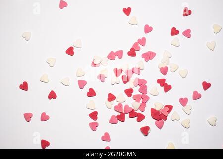 Süße Herzen. Rosa, rote und weiße herzförmige Zuckerstreuseln. Buntes Herz aus vielen kleinen Herzen. Valentinstag oder Muttertag Hintergrund Stockfoto