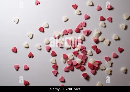 Süße Herzen. Rosa, rote und weiße herzförmige Zuckerstreuseln. Buntes Herz aus vielen kleinen Herzen. Valentinstag oder Muttertag Hintergrund Stockfoto