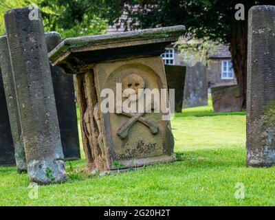 Eyam Dorfkirche Grabhof Schädel und Kreuzknochen Schnitzerei auf dem Grabstein aus der Beulenpest-Ära Stockfoto