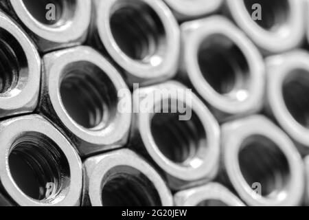 Metallmuttern in einer Reihe Hintergrund. Verchromte Schraubenmuttern. Muster der Stahlmuttern. Werkzeuge für die Arbeit. Stockfoto