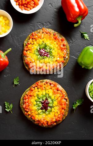 Rainbow Veggie Paprika Pizza auf schwarzem Stein Hintergrund. Vegetarisch vegan oder gesundes Lebensmittelkonzept. Draufsicht, flach liegend Stockfoto