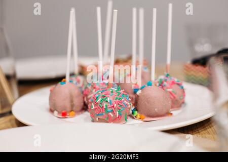 Viele kleine rosa Kuchen mit Streuseln auf einem großen weißen Teller Stockfoto