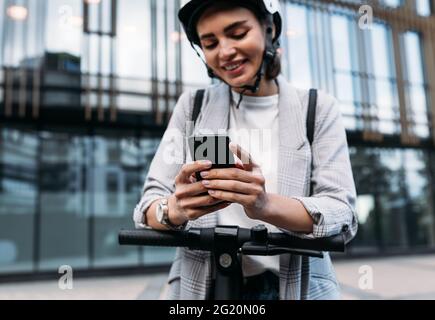 Nahaufnahme der Geschäftsfrau Hände halten Smartphone, während auf Elektroroller stehen Stockfoto