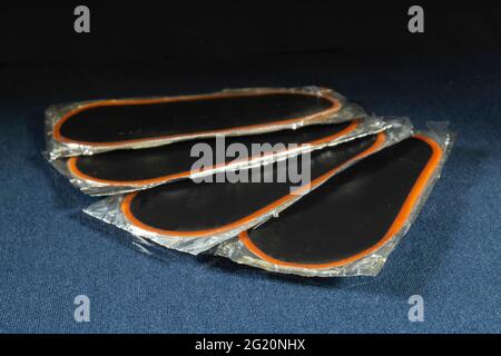 Gummiaufnäher für die Kamera auf dem Tisch mit Reflektion.Radreparaturteile auf schwarzem Hintergrund Stockfoto