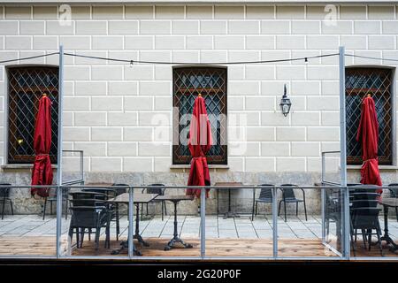 Eingestürzte Stühle und zusammengefaltete Sonnenschirme im Außenbereich eines Restaurants während der Corona-Pandemie. Stockfoto