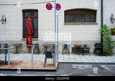 Eingestürzte Stühle und zusammengefaltete Sonnenschirme im Außenbereich eines Restaurants während der Corona-Pandemie. Stockfoto