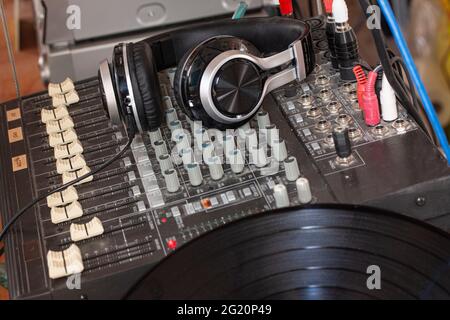 Altmodischer Musik-Sound-Mixer mit Kopfhörern. Professionelles Audio-Mischpult für DJ mit Tasten, Fadern und Schiebereglern. Kopfhörer liegen auf dem Mixer. Stockfoto