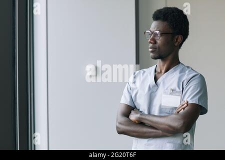 Porträt eines selbstbewussten afroamerikanischen Arztes in Uniform, der in der Klinik mit gekreuzten Armen steht und Platz kopiert Stockfoto