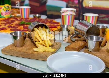 Köstliche pommes frites auf einem Schneidebrett in einer eisernen Tasse auf einem Tischhintergrund Stockfoto