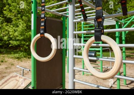 Hölzerne Gymnastikringe, die in einer Freilufthalle in einem Park hängen, selektiver Fokus. Stockfoto