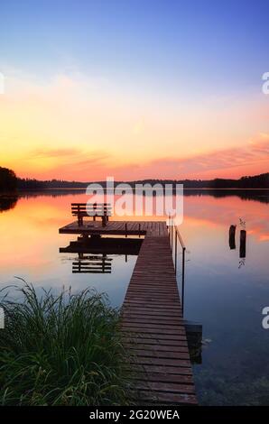 Bank auf einem hölzernen Pier bei Sonnenuntergang, Lipie Lake in Dlugie Village, Polen Stockfoto