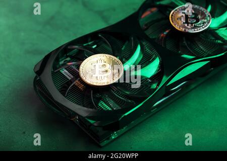 Goldbitcoin auf dem Grafikkarten-Kühler mit grüner Neonbeleuchtung im Cyberpunk-Stil. Das Konzept der Bergbau und Bergbau von Kryptowährungen, die devic Stockfoto