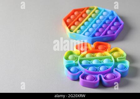 Neue beliebte Silikon bunte Antistress Pop it Spielzeug für Kind auf hellem Hintergrund. Einfache Grübchen. Speicherplatz kopieren Stockfoto