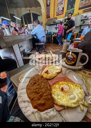 Zwei Rühreier auf Scheiben Schinken, Bohnen und amerikanischem Kaffee in einer Guns and Roses Tasse im Cafe Cele auf dem städtischen Markt von Hermosillo, Mexiko. Frühstück, Lebensmittel und Nahrungen, Mahlzeiten, Lebensmittel. (Foto von Luis Gutierrez / Norte Photo) Dos huevos estrellados sobre rebanadas de jamon, frijoles y Cafe americano en tasa de Guns and Roses en el Cafe Cele del Mercado Municipal de Hermosillo, Mexiko. Desayuno, Alimentos, comida, Comidas, Essen. (Foto von Luis Gutierrez/ Norte Photo) Stockfoto