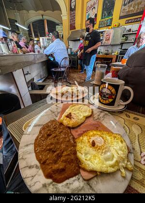 Zwei Rühreier auf Scheiben Schinken, Bohnen und amerikanischem Kaffee in einer Guns and Roses Tasse im Cafe Cele auf dem städtischen Markt von Hermosillo, Mexiko. Frühstück, Lebensmittel und Nahrungen, Mahlzeiten, Lebensmittel. (Foto von Luis Gutierrez / Norte Photo) Dos huevos estrellados sobre rebanadas de jamon, frijoles y Cafe americano en tasa de Guns and Roses en el Cafe Cele del Mercado Municipal de Hermosillo, Mexiko. Desayuno, Alimentos, comida, Comidas, Essen. (Foto von Luis Gutierrez/ Norte Photo) Stockfoto