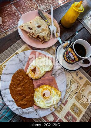 Zwei Rühreier auf Scheiben Schinken, Bohnen und amerikanischem Kaffee in einer Guns and Roses Tasse im Cafe Cele auf dem städtischen Markt von Hermosillo, Mexiko. Frühstück, Lebensmittel und Nahrungen, Mahlzeiten, Lebensmittel. (Foto von Luis Gutierrez / Norte Photo) Dos huevos estrellados sobre rebanadas de jamon, frijoles y Cafe americano en tasa de Guns and Roses en el Cafe Cele del Mercado Municipal de Hermosillo, Mexiko. Desayuno, Alimentos, comida, Comidas, Essen. (Foto von Luis Gutierrez/ Norte Photo) Stockfoto