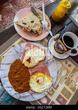 Zwei Rühreier auf Scheiben Schinken, Bohnen und amerikanischem Kaffee in einer Guns and Roses Tasse im Cafe Cele auf dem städtischen Markt von Hermosillo, Mexiko. Frühstück, Lebensmittel und Nahrungen, Mahlzeiten, Lebensmittel. (Foto von Luis Gutierrez / Norte Photo) Dos huevos estrellados sobre rebanadas de jamon, frijoles y Cafe americano en tasa de Guns and Roses en el Cafe Cele del Mercado Municipal de Hermosillo, Mexiko. Desayuno, Alimentos, comida, Comidas, Essen. (Foto von Luis Gutierrez/ Norte Photo) Stockfoto