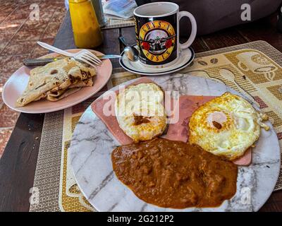 Zwei Rühreier auf Scheiben Schinken, Bohnen und amerikanischem Kaffee in einer Guns and Roses Tasse im Cafe Cele auf dem städtischen Markt von Hermosillo, Mexiko. Frühstück, Lebensmittel und Nahrungen, Mahlzeiten, Lebensmittel. (Foto von Luis Gutierrez / Norte Photo) Dos huevos estrellados sobre rebanadas de jamon, frijoles y Cafe americano en tasa de Guns and Roses en el Cafe Cele del Mercado Municipal de Hermosillo, Mexiko. Desayuno, Alimentos, comida, Comidas, Essen. (Foto von Luis Gutierrez/ Norte Photo) Stockfoto