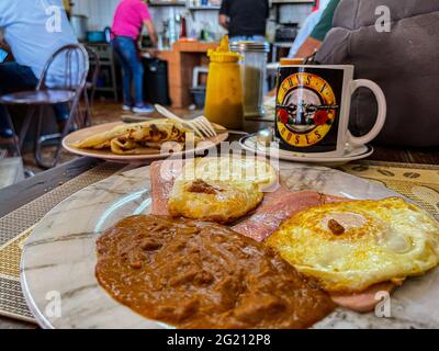 Zwei Rühreier auf Scheiben Schinken, Bohnen, Mehltortillas und amerikanischem Kaffee in einer Guns and Roses Tasse im Cafe Cele auf dem städtischen Markt von Hermosillo, Mexiko. Frühstück, Lebensmittel und Nahrungen, Mahlzeiten, Lebensmittel. (Foto von Luis Gutierrez / Norte Photo) Dos huevos estrellados sobre rebanadas de jamon, frijoles, tortillas de harina y Cafe americano en tasa de Guns and Roses en el Cafe Cele del Mercado Municipal de Hermosillo, Mexiko. Desayuno, Alimentos, comida, Comidas, Essen. (Foto von Luis Gutierrez/ Norte Photo) Stockfoto