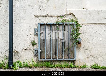 Metallstangen und Vorhängeschloss über ausgediente, vernagelten Fenstern Stockfoto