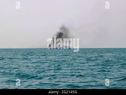 Das Fährschiff der Bucht von Bengalen raucht aus seinem Kamin. Schwarze Abgase, die nach der Zündung des Hauptmotors aus dem Kamin eines festgetäuten Tankers stammen. Stockfoto