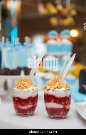 Köstliche Desserts in Glasküssen mit weißen Löffeln, serviert auf einer Geburtstagsparty Stockfoto