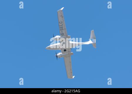 Diamond da 42 Twin Star Leichtflugzeug G-SELC fliegt in klarem blauen Himmel über dem London Southend Airport, Essex, Großbritannien. Über Kopf in Höhe Stockfoto