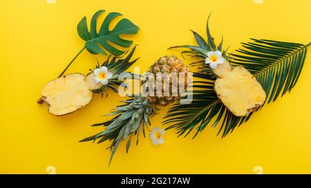 Ananas ganze tropische Sommer Ananas Früchte und geschnittene Ananas Hälften mit tropischen Plumeria Blumen flach Lay Zusammensetzung auf gelbe Farbe Stockfoto