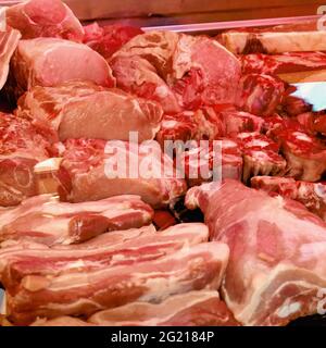 Rohe Schweinefleisch- und Rindfleischstücke aufgereiht und zum Verkauf bereit. Unter anderem Pancetta, Knochenmark, Schnitzel, Sattelrückenfilet, Usw. Stockfoto