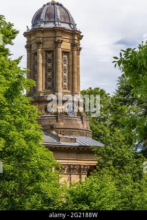 Der Turm der Saltaire United Reformed Church, der durch Bäume in West Yorkshire gesehen wird. Die viktorianische Kirche wurde von Sir Titus Salt erbaut. Stockfoto