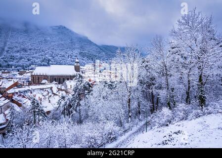 Brasov, Siebenbürgen. Winternachtslandschaft mit schwarzer Kirche und Karpaten, Winterreise in Rumänien. Stockfoto