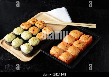Ein Satz Rollen mit Essstäbchen und Papierservietten auf schwarzem Holzhintergrund. Selektiver Fokus. Stockfoto