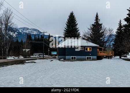 REVELSTOKE, KANADA - 14. MÄRZ 2021: Privathaus und Straßenansicht in Kleinstadt Abendzeit früher Frühling mit Schnee Stockfoto