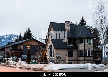 REVELSTOKE, KANADA - 14. MÄRZ 2021: Privathaus und Straßenansicht in Kleinstadt Abendzeit früher Frühling mit Schnee Stockfoto