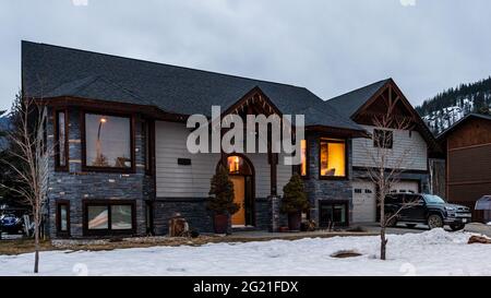 REVELSTOKE, KANADA - 14. MÄRZ 2021: Privathaus und Straßenansicht in Kleinstadt Abendzeit früher Frühling mit Schnee Stockfoto