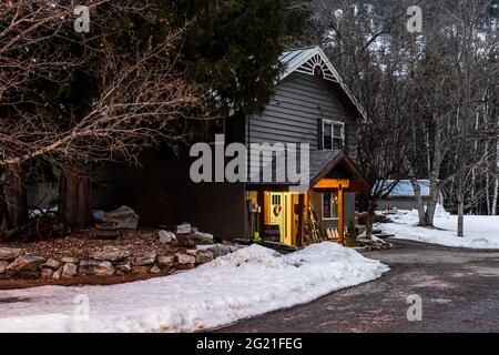 REVELSTOKE, KANADA - 14. MÄRZ 2021: Privathaus und Straßenansicht in Kleinstadt Abendzeit früher Frühling mit Schnee Stockfoto