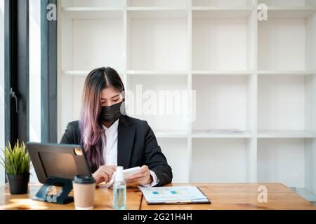 Geschäftsfrau mit einem Taschenrechner, um die Arbeit am Schreibtisch im Heimbüro zu berechnen. Berater,Finanzberater,Finanzberater und Rechnungswesen Stockfoto