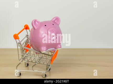 Ein Trolley mit einem Sparschwein auf dem Tisch.das Konzept des Einkaufs oder Sparens Stockfoto