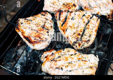 Appetitlich gegrilltes Schweinekotelett auf flammendem Grill. Saftiges und leckeres Fleisch auf einem Metalldrahtgestell. Stockfoto