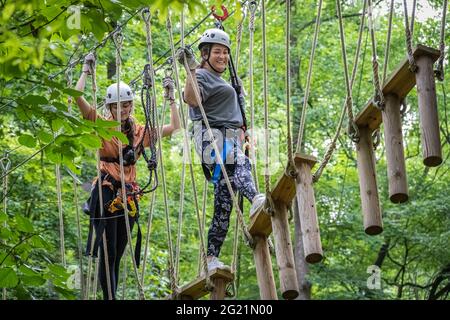 Zwei Frauen navigieren durch schwingende Baumwalk-Brücken in den Screaming Eagle Aerial Adventures des Chattahoochee Nature Center in Roswell, Georgia. (USA) Stockfoto