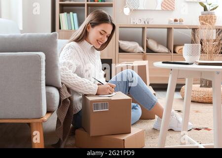 Junge Frau bereitet Paket für Client zu Hause Stockfoto