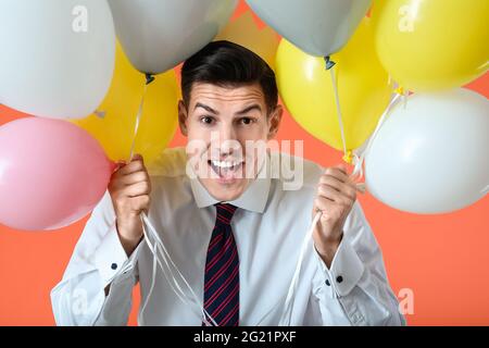 Happy Handsome Mann mit Ballons auf farbigem Hintergrund Stockfoto