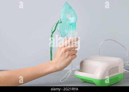 Frau mit Vernebler auf grauem Hintergrund Stockfoto
