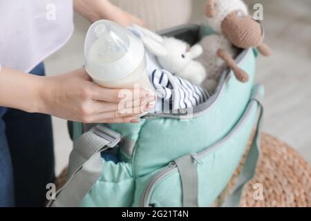 Frau, die eine Flasche Milch für das Baby in einen Beutel legt, Nahaufnahme Stockfoto