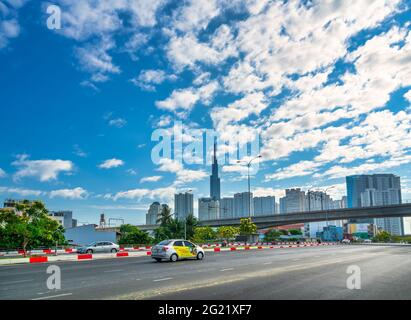 Der Verkehr auf der Brücke neben dem Hochhausgebiet am Fluss stellt eine florierende wirtschaftliche Entwicklung in der dynamischen Stadt Ho Chi Minh in Vietnam dar Stockfoto